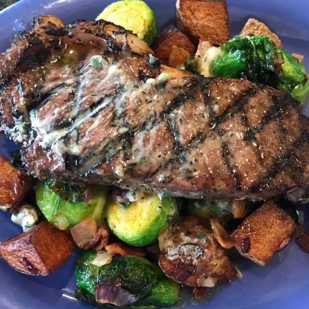 Steak on a bed of brussel sprouts and potatoes