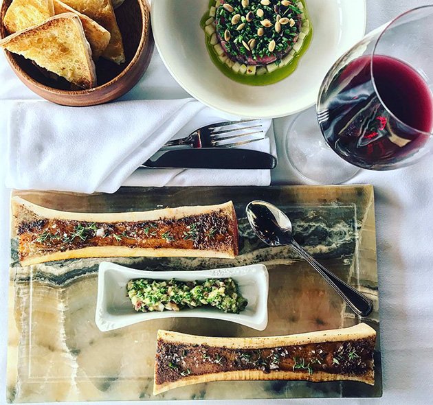 Beef dish with a side of bread and a glass of wine