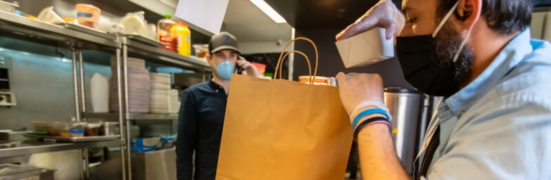 Men in masks bagging food for delivery