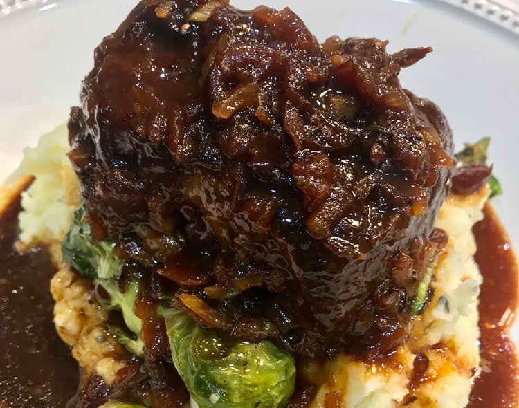 Cranberry-braised short ribs over a bed of garlic mashed potatoes and Brussel sprouts