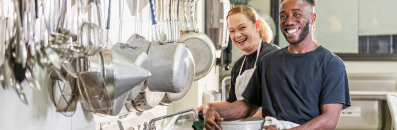 Kitchen staff smiling while washing dishes